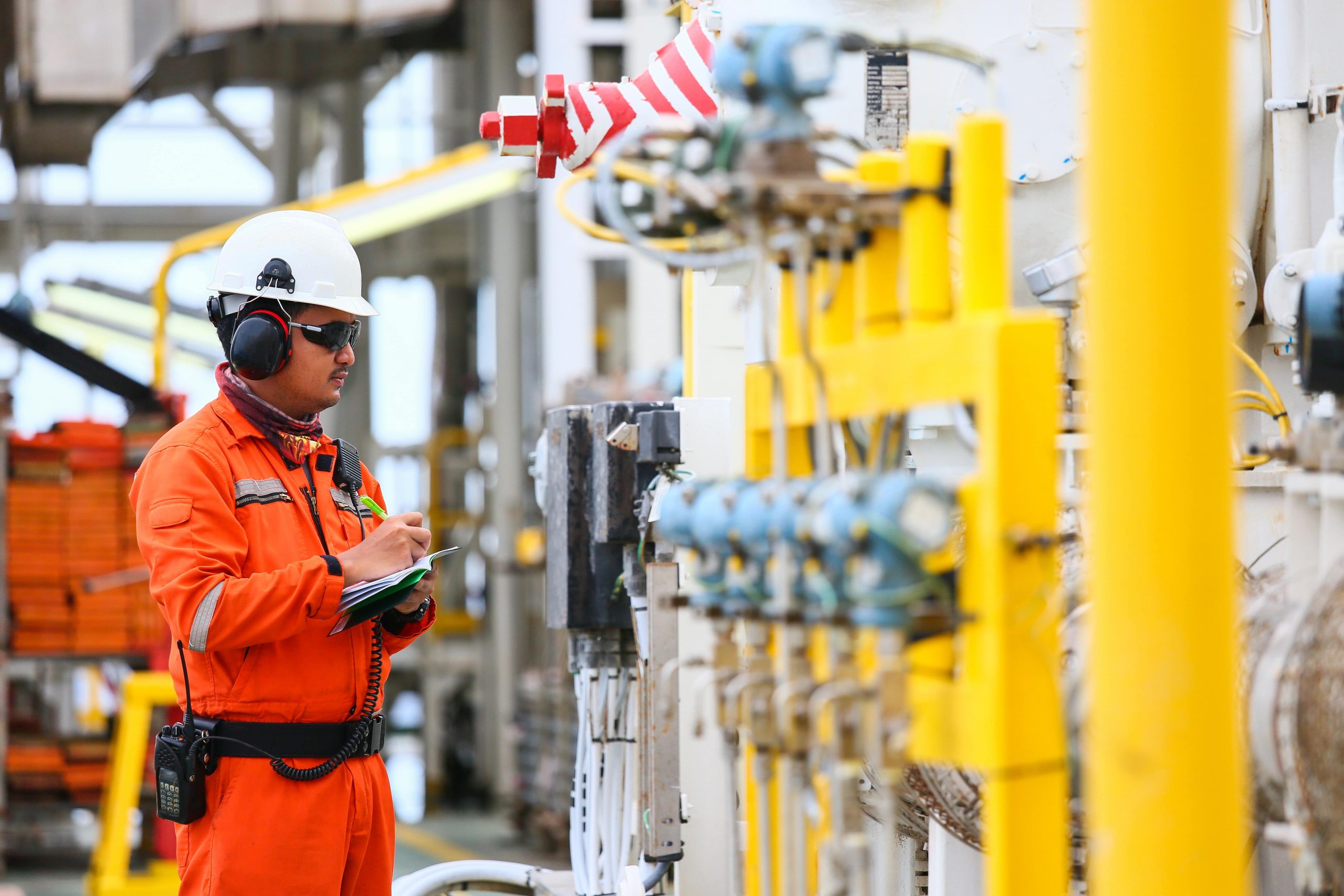 ShowEquip covers the Oil and Gas sector / industry. Image of worker making notes whilst looking at a panel.